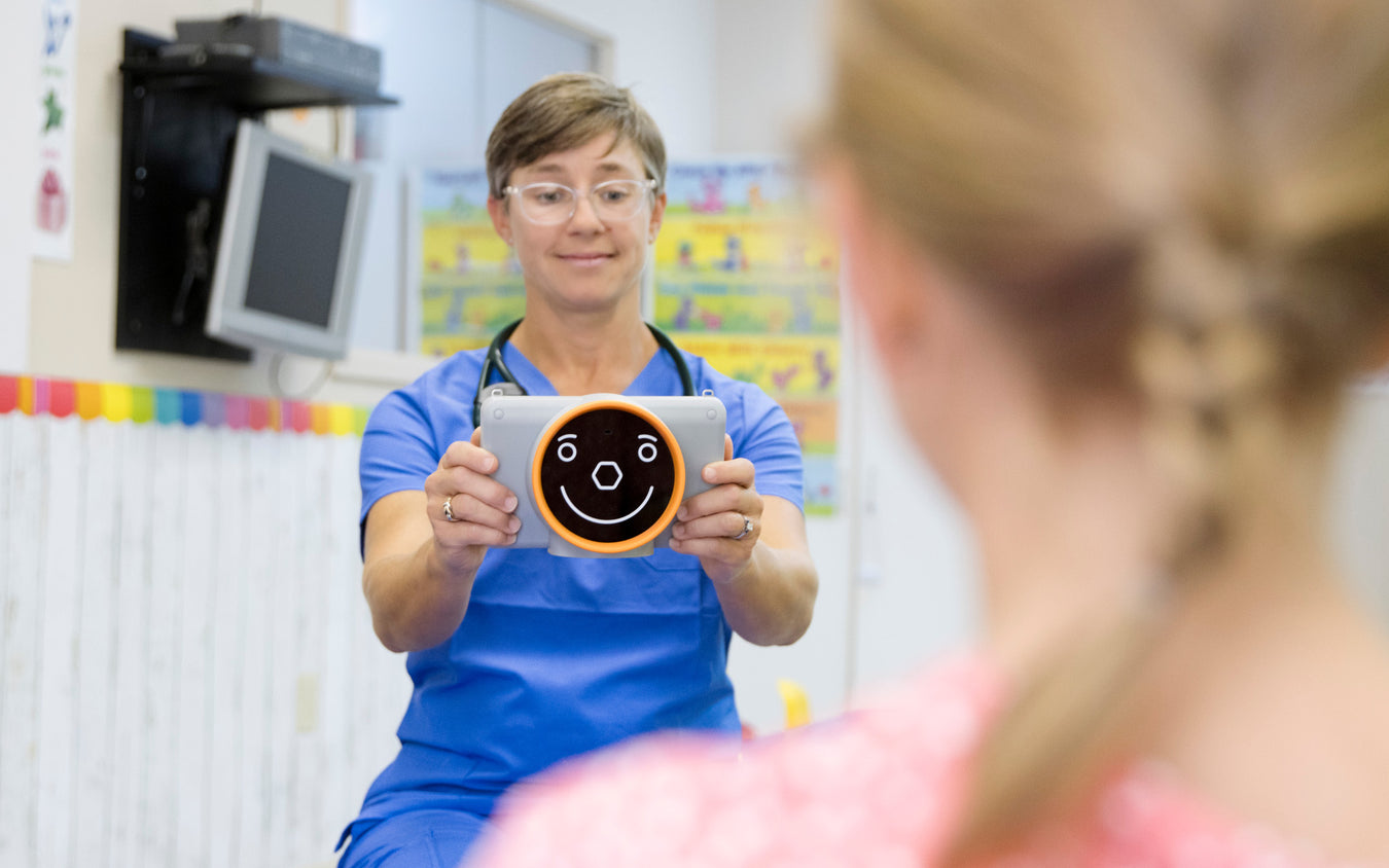 Nurse holding a tablet with a smiley face in a healthcare setting